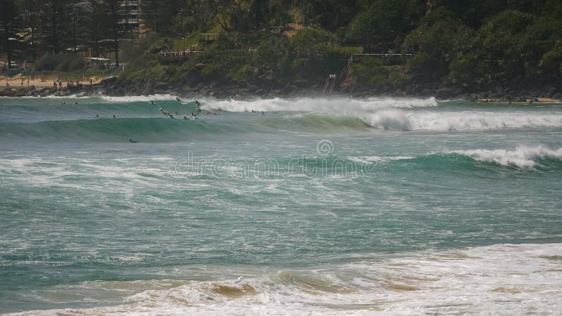 Posibilidad muy remota de las personas que practica surf que montan ondas en el greenmount en el Gold Coast de Queensland fotos de archivo Posibilidad muy remota de las personas que practica surf que montan ondas en el greenmount en el Gold Coast de Queensland fotos de archivo