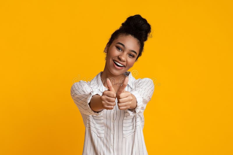 I Like It. Positive Black Woman Gesturing Thumbs Up AT Camera And Smiling, Posing Over Yellow Studio Background With Free Space. I Like It. Positive Black Woman Gesturing Thumbs Up AT Camera And Smiling, Posing Over Yellow Studio Background With Free Space
