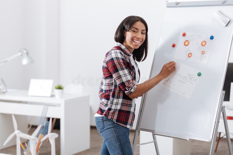 Positieve gelukkige vrouw die zich dichtbij whiteboard bevinden royalty-vrije stock fotografie Positieve gelukkige vrouw die zich dichtbij whiteboard bevinden royalty-vrije stock fotografie
