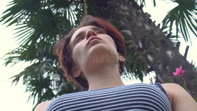 Position de jeune femme sur le remblai sous le palmier