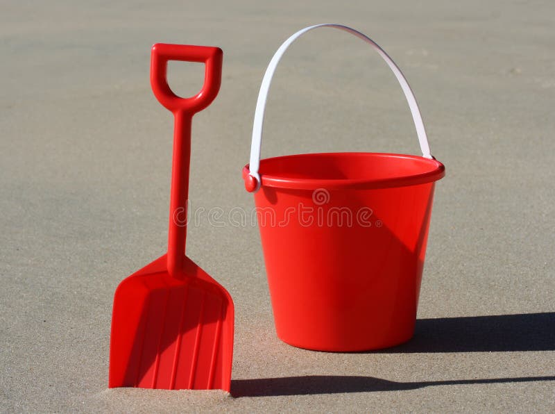 A red plastic bucket and spade on the beach. A red plastic bucket and spade on the beach