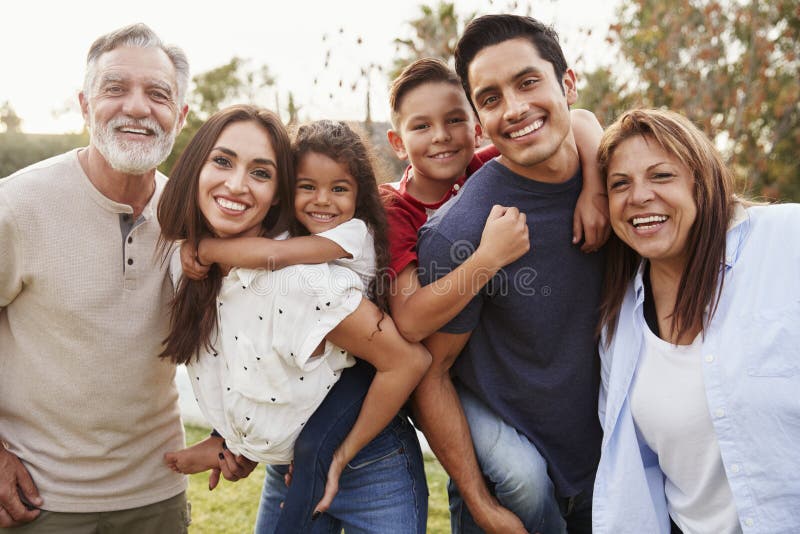 Position hispanique de famille de trois générations en parc, souriant à la caméra, foyer sélectif