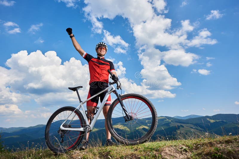 Position professionnelle heureuse de cycliste de sportif avec la bicyclette de pays croisé sur une colline, main rasing photos libres de droits Position professionnelle heureuse de cycliste de sportif avec la bicyclette de pays croisé sur une colline, main rasing photos libres de droits