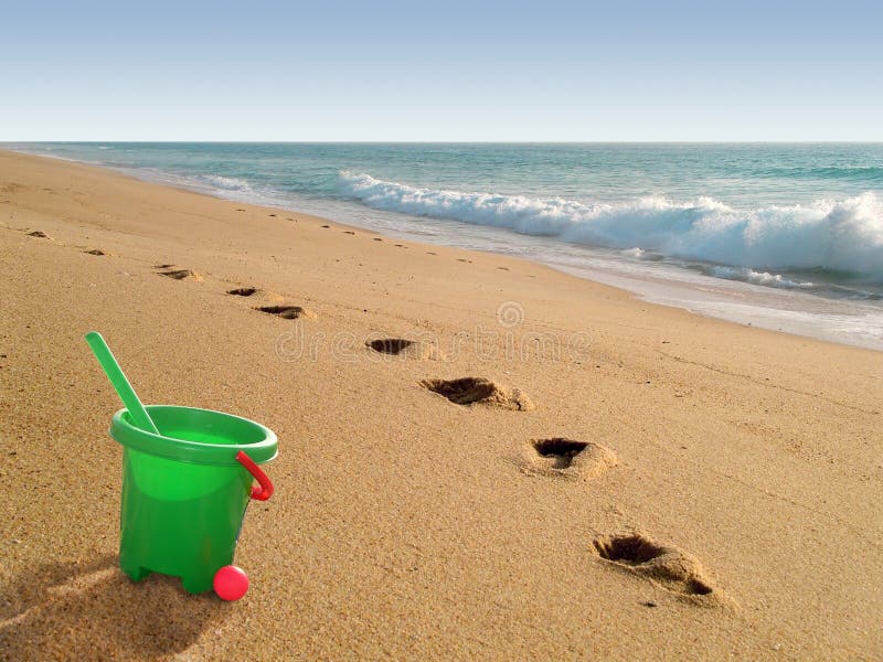 Beach with plastic green bucket and footprints on sand. Beach with plastic green bucket and footprints on sand.