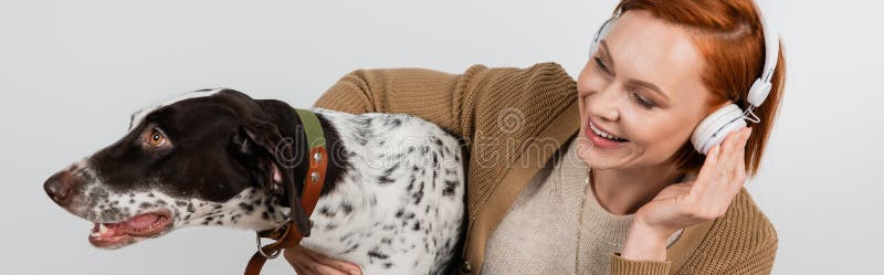Positiv kvinna i hörlurar som kramar dalmatiker arkivbilder