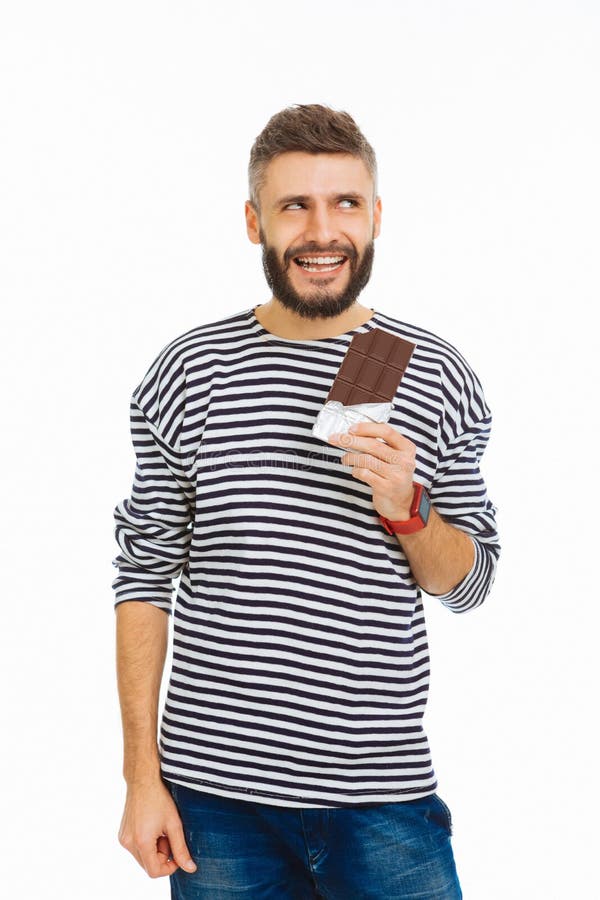 Positiv stilig man som tycker om hans chokladstång fotografering för bildbyråer Positiv stilig man som tycker om hans chokladstång fotografering för bildbyråer