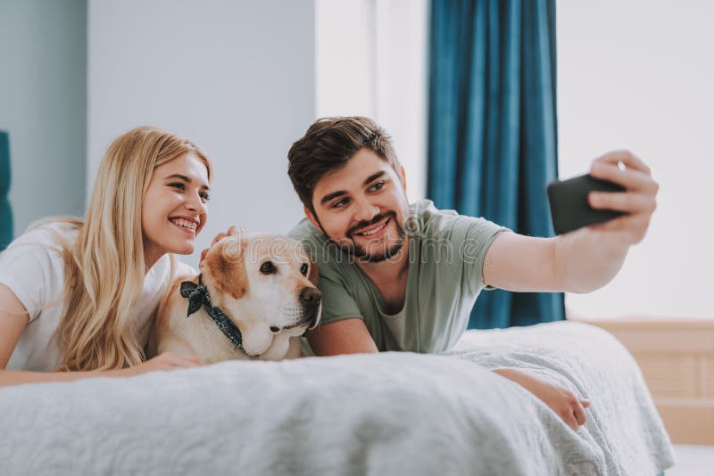 Positiv ung coule som gör selfie med deras hund royaltyfria foton Positiv ung coule som gör selfie med deras hund royaltyfria foton