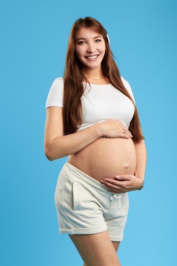 Positive beautiful young woman with big belly looking at the camera stock photo Positive beautiful young woman with big belly looking at the camera stock photo