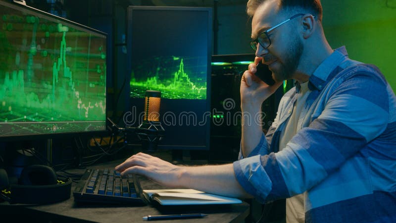 Positive Caucasian man worker male guy employer smile typing keyboard computer talking mobile phone. Happy crypto trader royalty free stock photo