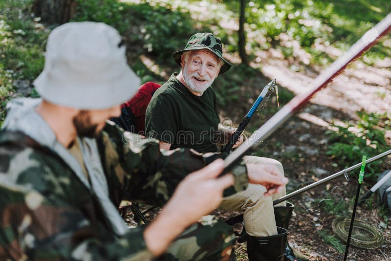 Joyful retired man enjoying fishing with his son stock image Joyful retired man enjoying fishing with his son stock image