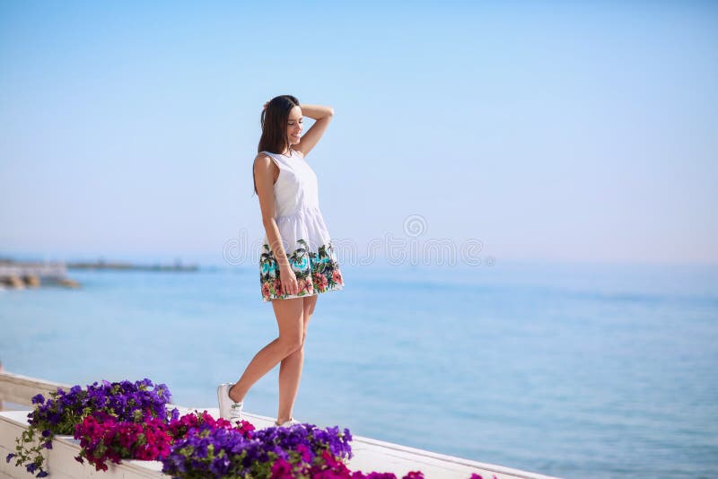 A positive and healthy female on a sea background. Full-lengths of a beautiful girl laughing near a sea beach. Summer vacation.