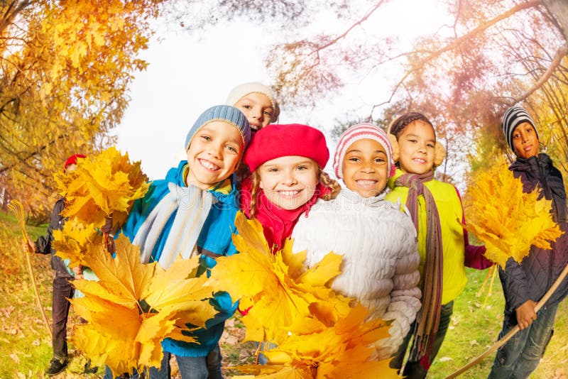 Positive kids with bunch of yellow maple leaves