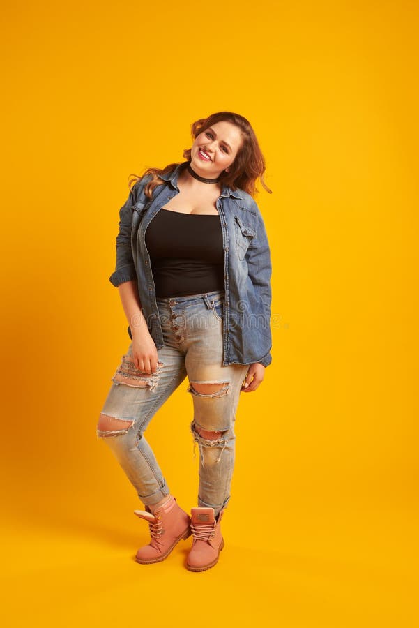Full-length portrait of positive plus-size model smiling at camera
