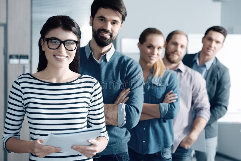 Positive woman and her team standing in the office stock photography Positive woman and her team standing in the office stock photography