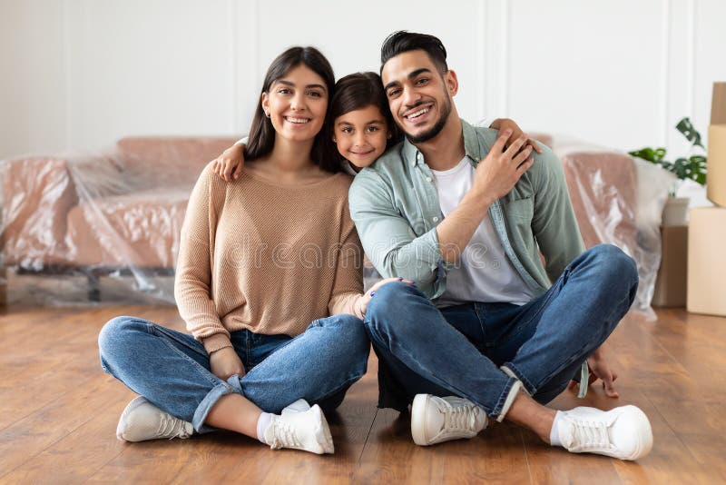 Positive young family looking at camera, posing in new flat