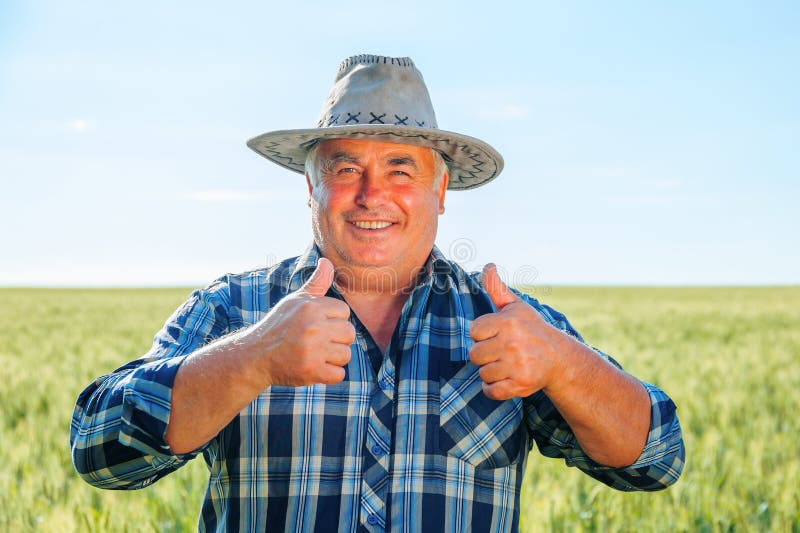 Positive ältere männliche Arbeiterin, die Kamera mit Daumen anschauen lizenzfreies stockfoto