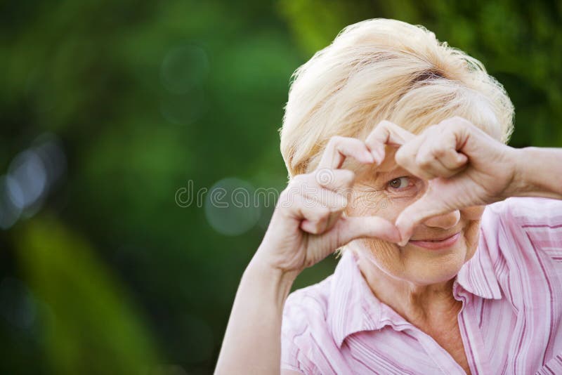 Positividade. Mulher superior engraçada feliz que mostra o símbolo do coração imagens de stock Positividade. Mulher superior engraçada feliz que mostra o símbolo do coração imagens de stock