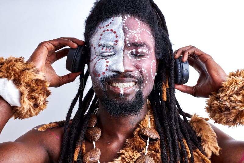 Positivo africano nativo hombre en desgaste étnico disfrutar de la música en los auriculares foto de archivo