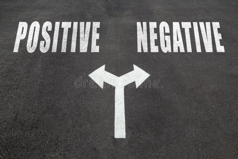 Positive vs negative choice concept, two direction arrows on asphalt. Positive vs negative choice concept, two direction arrows on asphalt.