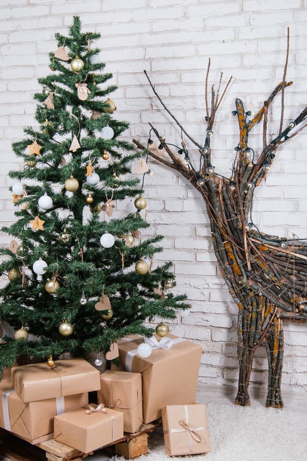 Posizione del ` s del nuovo anno nello studio con un cervo, decorato con un albero di Natale, regali, un canestro dei coni fotografia stock Posizione del ` s del nuovo anno nello studio con un cervo, decorato con un albero di Natale, regali, un canestro dei coni fotografia stock