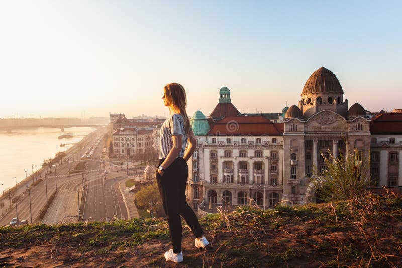 Posição bonita da mulher oposto à fachada famosa e entrada ao hotel Gellert em bancos de Danúbio em Budapest, Hungria fotos de stock royalty free Posição bonita da mulher oposto à fachada famosa e entrada ao hotel Gellert em bancos de Danúbio em Budapest, Hungria fotos de stock royalty free