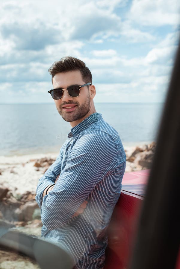 posição de sorriso considerável do homem no carro perto do mar durante foto de stock royalty free posição de sorriso considerável do homem no carro perto do mar durante foto de stock royalty free