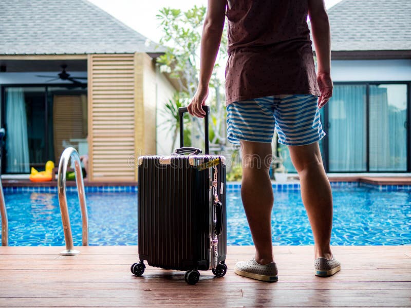 Posição do homem novo com a mala de viagem do curso pela associação Bandeira de viagem do projeto de conceito das férias de verão fotografia de stock Posição do homem novo com a mala de viagem do curso pela associação Bandeira de viagem do projeto de conceito das férias de verão fotografia de stock