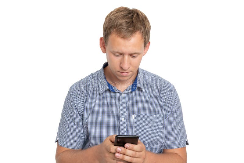 Posição do homem novo que olha sua tela do telefone, conversando com amigo, camisa azul vestindo isolada no fundo branco imagens de stock royalty free Posição do homem novo que olha sua tela do telefone, conversando com amigo, camisa azul vestindo isolada no fundo branco imagens de stock royalty free