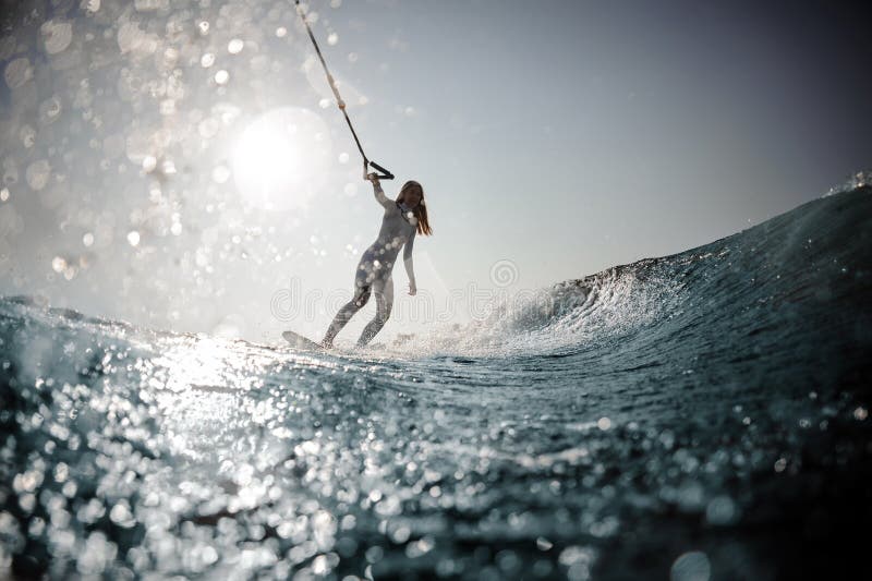 Posição loura da menina no wakeboard que guarda uma corda imagens de stock royalty free Posição loura da menina no wakeboard que guarda uma corda imagens de stock royalty free