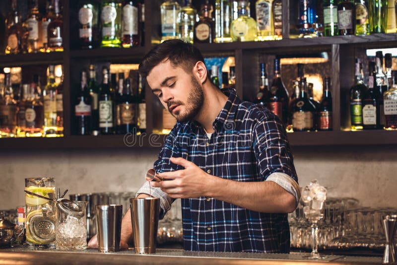 Posição nova do barman no ingrediente de derramamento do contador da barra no abanador concentrado imagem de stock Posição nova do barman no ingrediente de derramamento do contador da barra no abanador concentrado imagem de stock