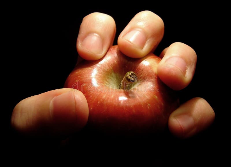 Hand appearing in the dark and grabbing an apple. Hand appearing in the dark and grabbing an apple