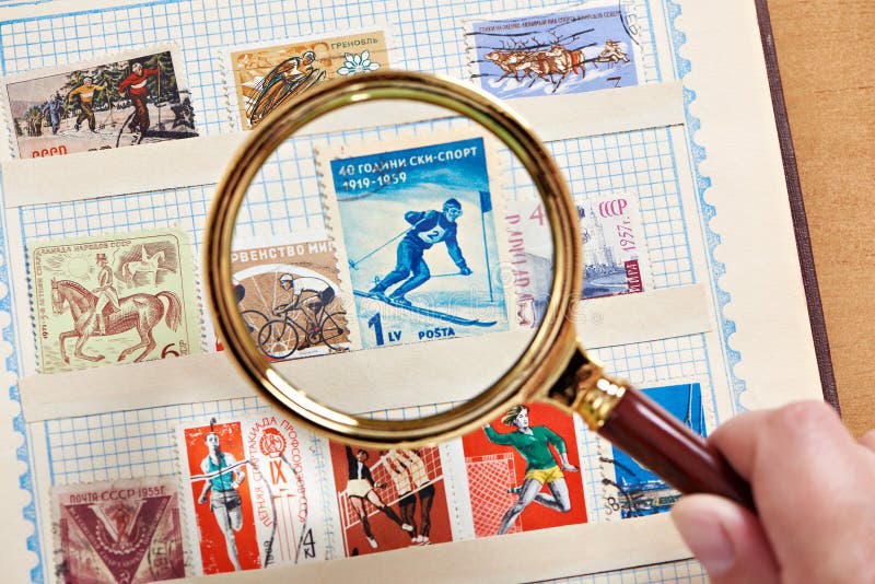 Postage sport stamp with skier under magnifier on album
