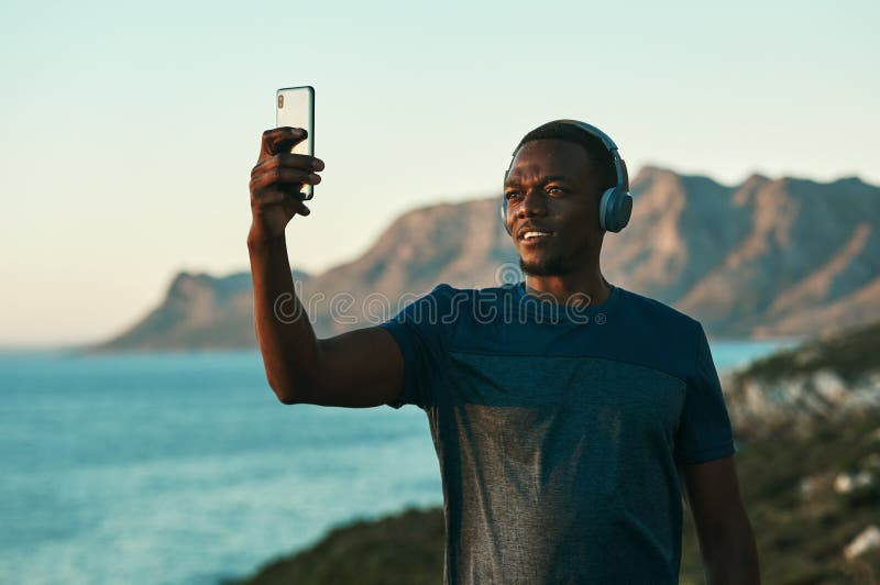 Cropped photo of a young man taking a selfie while standing outdoors. Cropped photo of a young man taking a selfie while standing outdoors