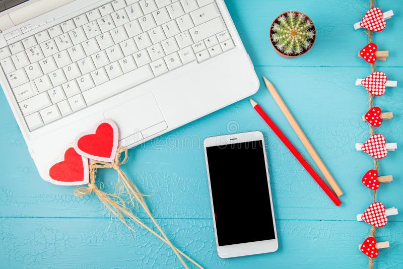 Posto di lavoro su un fondo blu del computer portatile, su uno smartphone e sui cuori decorativi rossi, matite Giorno di S. Valen fotografia stock libera da diritti Posto di lavoro su un fondo blu del computer portatile, su uno smartphone e sui cuori decorativi rossi, matite Giorno di S. Valen fotografia stock libera da diritti