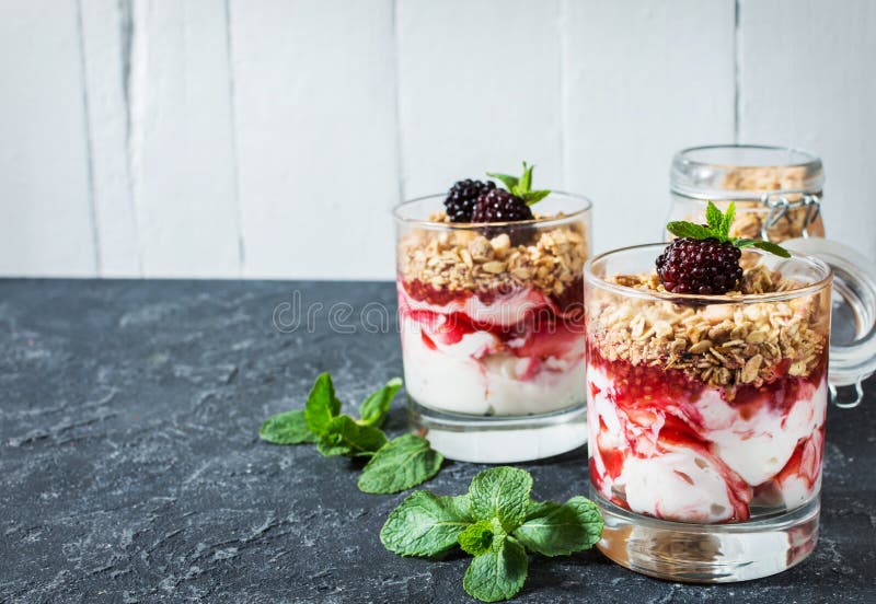Postre acodado sano con el yogur, granola, atasco, zarzamora en vidrio en el fondo de piedra imagen de archivo libre de regalías Postre acodado sano con el yogur, granola, atasco, zarzamora en vidrio en el fondo de piedra imagen de archivo libre de regalías