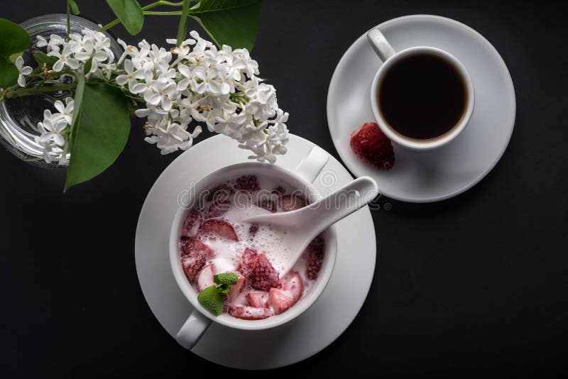 Postre, fresa con crema y rebanada de la menta, placa blanca, taza de café, fondo negro, visión superior imagen de archivo Postre, fresa con crema y rebanada de la menta, placa blanca, taza de café, fondo negro, visión superior imagen de archivo