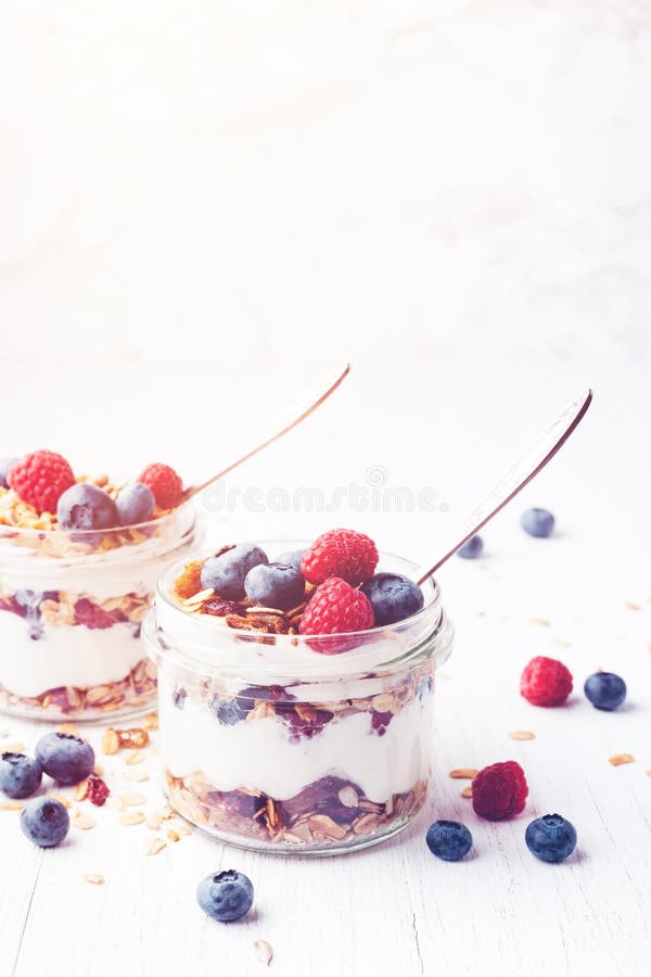 Postre helado con el granola, las bayas y el yogur en tarros fotos de archivo Postre helado con el granola, las bayas y el yogur en tarros fotos de archivo