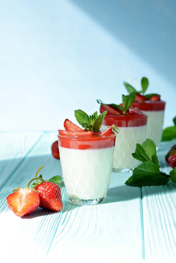 Postre italiano Panakota con los peones de la fresa, las bayas frescas y la menta en un fondo azul con las sombras duras Leche cr imagen de archivo libre de regalías Postre italiano Panakota con los peones de la fresa, las bayas frescas y la menta en un fondo azul con las sombras duras Leche cr imagen de archivo libre de regalías