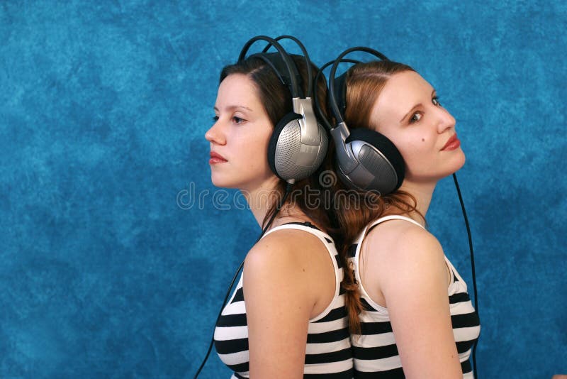 Two beautiful young woman wearing headphones and listen to music. Two beautiful young woman wearing headphones and listen to music.