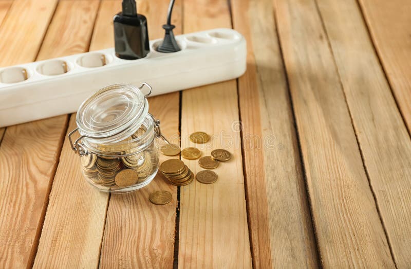 Pot avec des pièces de monnaie et bande de puissance sur le fond en bois Concept d'?conomie de l'?lectricit? images stock Pot avec des pièces de monnaie et bande de puissance sur le fond en bois Concept d'?conomie de l'?lectricit? images stock