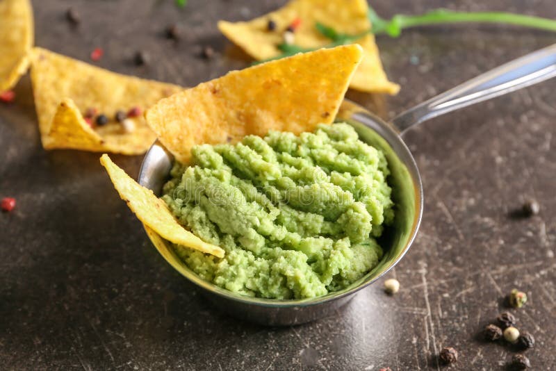 Pot with delicious guacamole and nachos on table royalty free stock photo