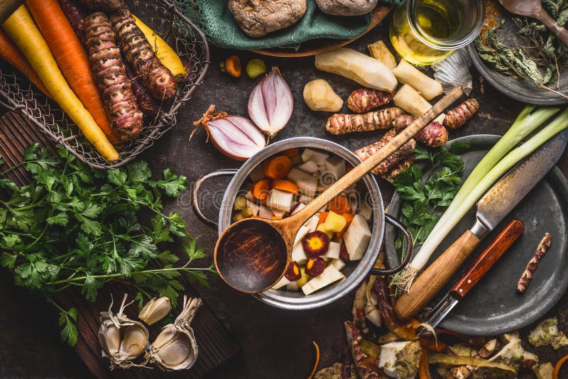 Pot with sliced colorful vegetables and cooking spoon on dark rustic table background with organic vegetarian ingredients and kitc stock images Pot with sliced colorful vegetables and cooking spoon on dark rustic table background with organic vegetarian ingredients and kitc stock images