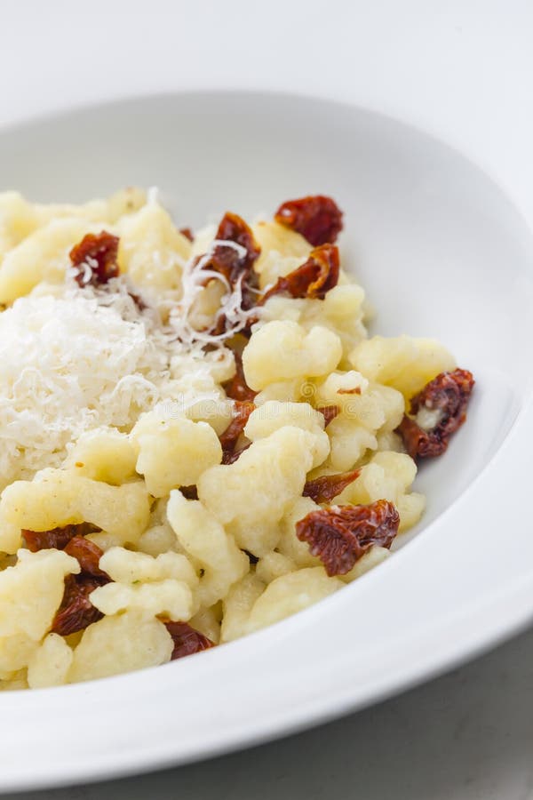 Potato dumplings called halusky with dry tomatoes and grated cheese