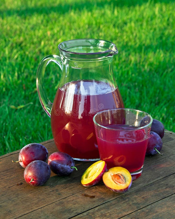 Poti il succo in un vetro ed in una caraffa con le prugne fotografie stock Poti il succo in un vetro ed in una caraffa con le prugne fotografie stock