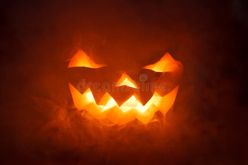 Potiron effrayant de Halloween regardant par la fumée. photo stock Potiron effrayant de Halloween regardant par la fumée. photo stock
