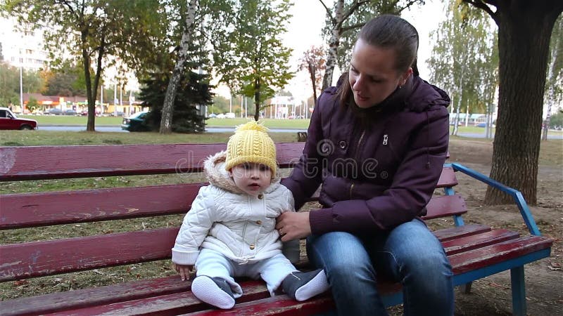 Potomstwa matkują z dziecka obsiadaniem na ławce w parku