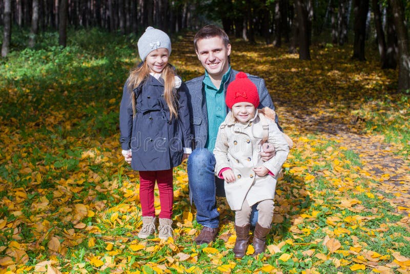Potomstwa ojcują i jego dwa uroczej małej córki chodzi w jesieni parkują słonecznego dzień i cieszą się