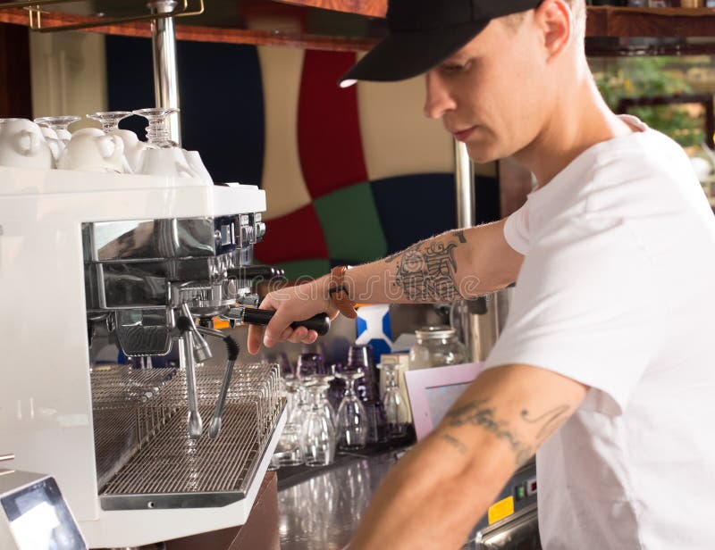 Potomstwa tattoed barista w sklep z kawą robi kawie używać com fotografia royalty free Potomstwa tattoed barista w sklep z kawą robi kawie używać com fotografia royalty free