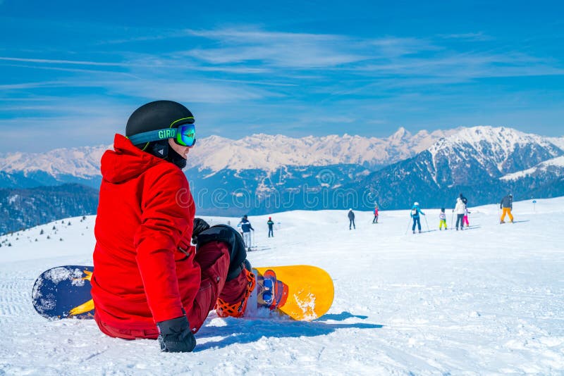 Potomstwa z snowboard mężczyzna obsiadaniem na wierzchołku góra fotografia royalty free Potomstwa z snowboard mężczyzna obsiadaniem na wierzchołku góra fotografia royalty free