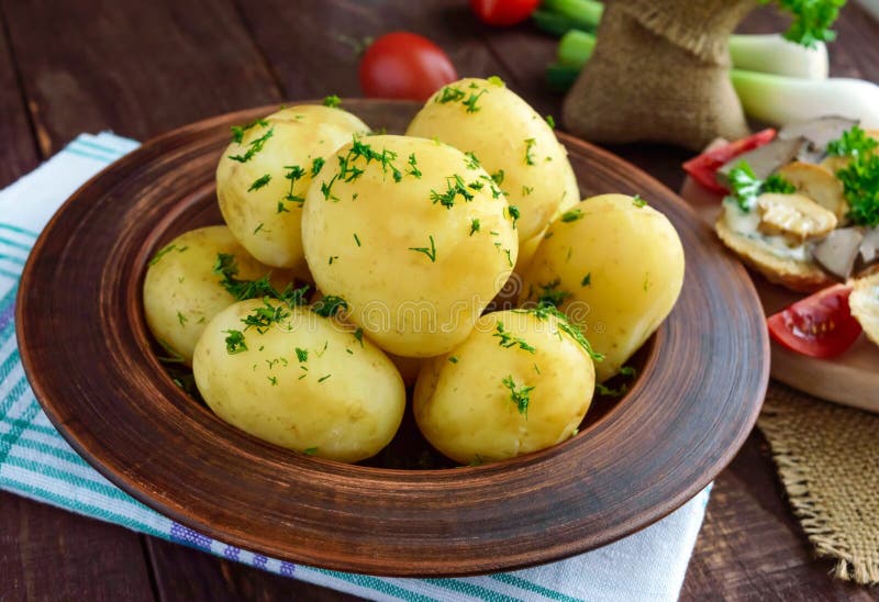 Potomstwo gotować się grule z masłem i koperem w glinianym pucharze fotografia stock